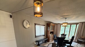 A kitchen with a granite countertop, wooden cabinets, a clock, and a dining area with a table and chairs.