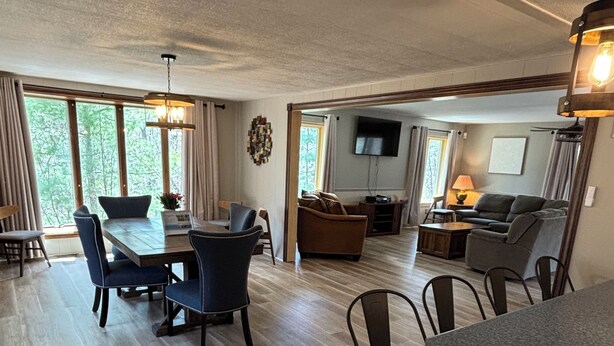 A spacious living area with a dining table, chairs, a sofa, and a TV.
