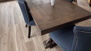 A dining area with a wooden table, blue upholstered chairs, and a vase with flowers.