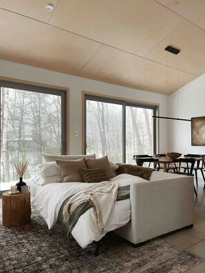 Une chambre moderne avec un grand lit, un coin repas et de grandes fenêtres.