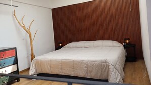 Ein Schlafzimmer mit einem Bett, Holzwandpaneelen, Nachttischen mit Lampen und einer Kommode.
