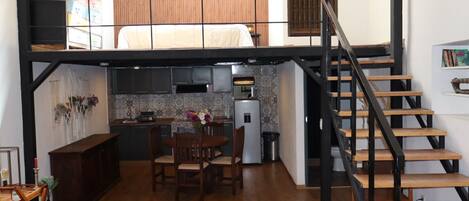 A compact kitchen with a dining area, a staircase, and a small seating area.
