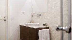 A modern bathroom with a white sink, a small potted plant, and a towel hanging on the door. - 196 Andrade Corvo Collection by Minhos Guest (Braga)