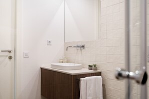 A modern bathroom with a white sink, a small potted plant, and a towel hanging on the door. - 196 Andrade Corvo Collection by Minhos Guest (Braga)