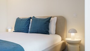 A neatly made bed with two pillows, a bedside lamp, and a wall socket. - 196 Andrade Corvo Collection by Minhos Guest (Braga)