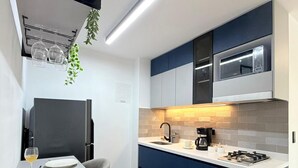 Une cuisine moderne avec un coin repas, comprenant une table blanche dressée avec des assiettes et des verres, un four à micro-ondes encastré et une machine à café.