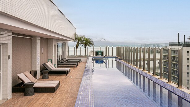 Area piscina sul tetto con poltronne relax e vista sulla città.