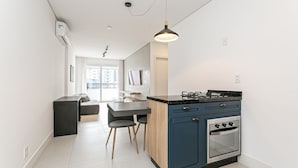 Una cucina moderna con forno integrato, una zona pranzo con tavolo e sedie, e una lampada a sospensione.