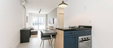 A modern kitchen with a built-in oven, a dining area with a table and chairs, and a pendant light.