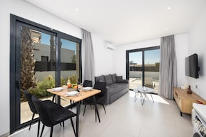 Una sala moderna con sofá, mesa de comedor, sillas y televisor.