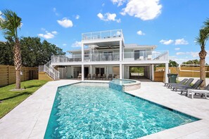 A two-story house with a swimming pool, outdoor seating, and a covered patio.