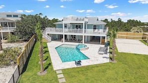 A two-story house with a swimming pool, a covered patio, and a fenced yard.