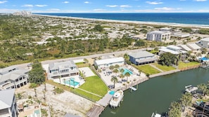 A coastal hotel with a pool, dock, and views of the beach and ocean.