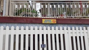 Cercado branco com piquetes e uma placa com a inscrição 'Bienvenue Maison Yzidee' e o número '22' na fachada de um edifício.