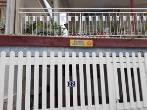 Ein weißer Zierzaun mit einem Schild, auf dem 'Bienvenue Maison Yzidee' und die Nummer '22' an einer Gebäudefassade stehen.