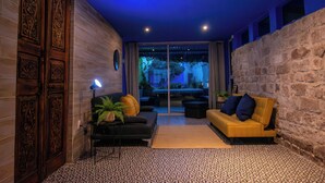 Un interior moderno con un sofá negro y amarillo, una mesita con una planta y un suelo estampado.