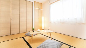 A traditional Japanese room with tatami flooring, a low table with cups and a plant, and sliding doors.