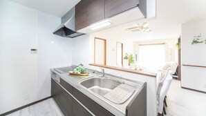 A modern kitchen with a double sink, dark cabinetry, and a stainless steel range hood.
