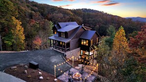 Une maison moderne dotée d’une grande terrasse, entourée d’un paysage boisé.