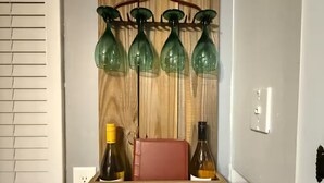 A wooden wall-mounted shelf with four green glass bottles, a red book, and a wooden box labeled "JUNE".