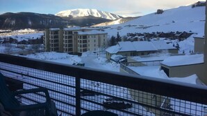 A snowy mountain landscape with a building in the foreground. - Cozy Condo | Stunning Mountain Views + Fireplace (Crested Butte)