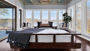 A bedroom with a large bed, a hanging chair, and a view of the outdoors. - Private 7BR Lakehouse Estate Pool Hottub 13 Beds (Lizella)