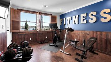 A gym with a large window, a wall with 'FITNESS' written on it, and various exercise equipment.