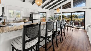 Een moderne keuken met witte kasten, een roestvrijstalen koelkast en een eethoek met zwarte stoelen en een houten tafel.