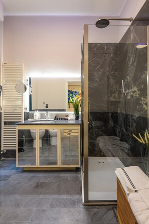 Un baño moderno con ducha de vidrio, tocador con espejo y retrete.