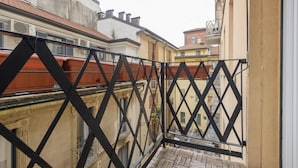 A narrow balcony with a black metal railing, overlooking a street with buildings. - DibraLuxurySuites (Milan)