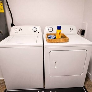 Two white front-loading washing machines with control panels, a wooden tray with a yellow bottle, and a black mat on the floor. - Waggoner in Longview (Longview)