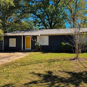 A single-story house with a front door, a small porch, and a well-maintained lawn.