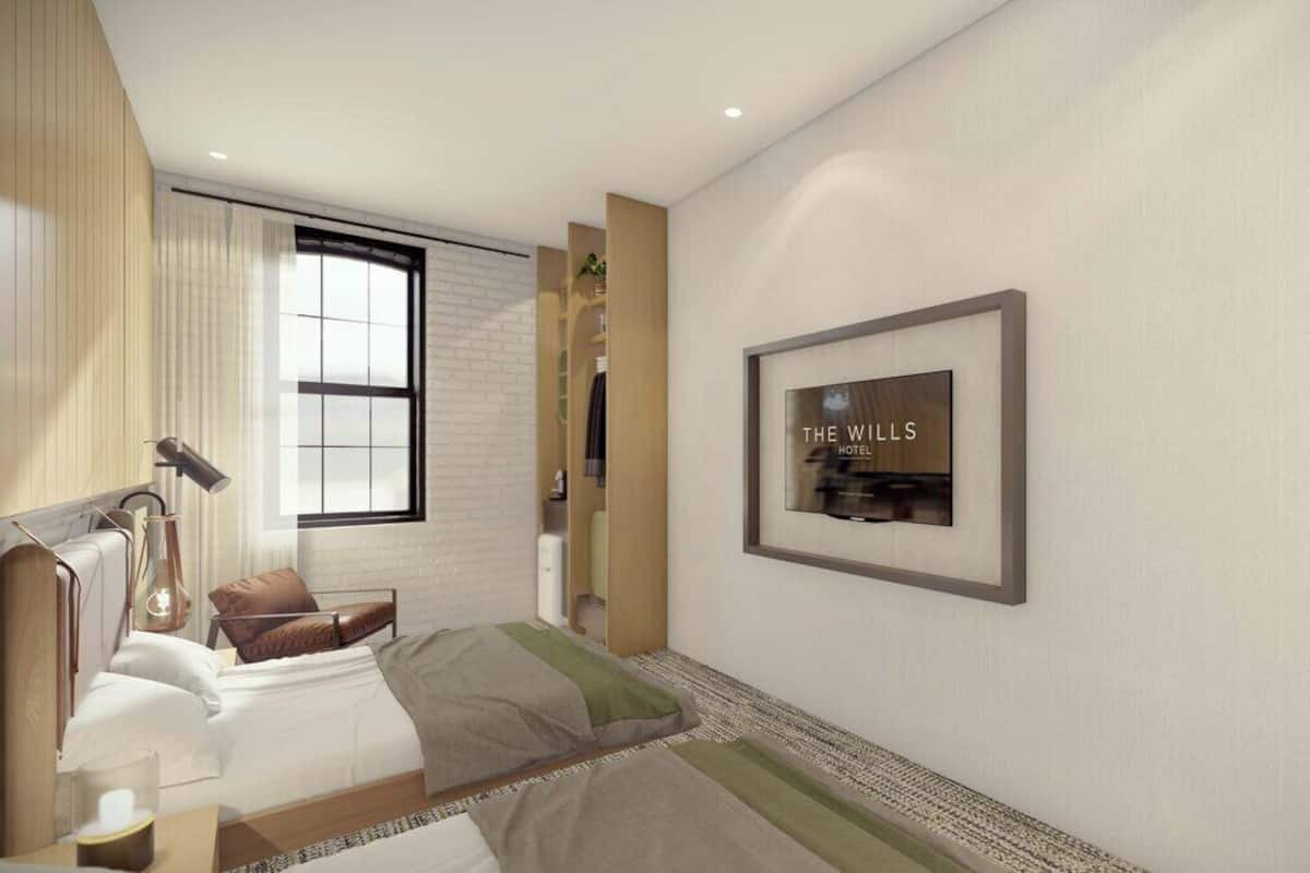 A modern hotel room with a bed, bedside table, lamp, and a framed sign on the wall.