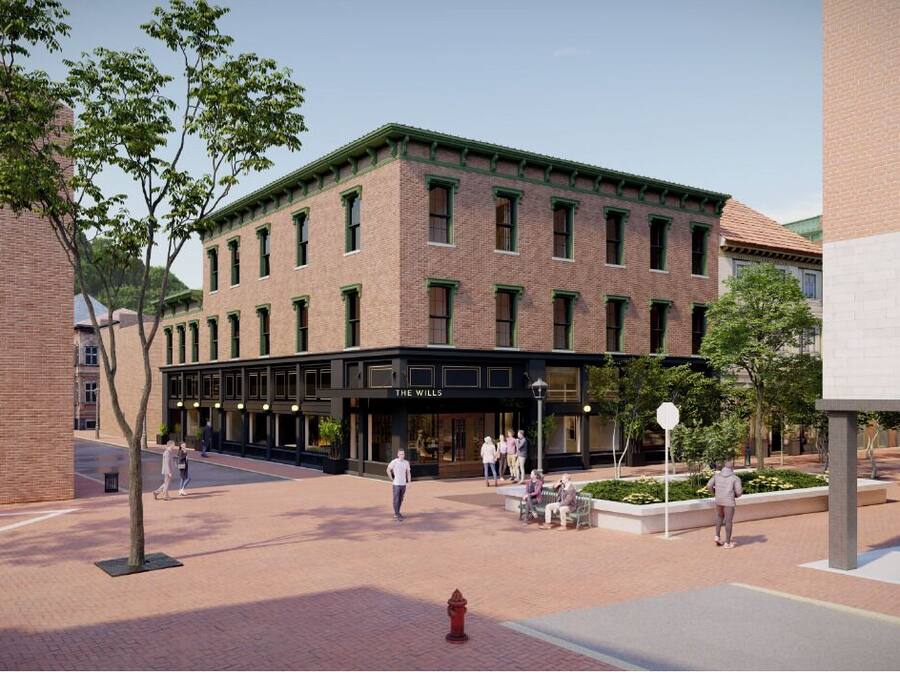 A brick building with a storefront labeled 'THE WILLS' and a pedestrian area with trees and benches.