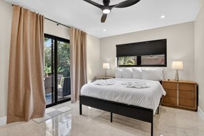 Un dormitorio moderno con una cama grande, ventilador de techo y vistas al exterior.