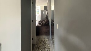 En smal gang med et mønstret gulv, der fører til et rum med en seng og et køleskab.
