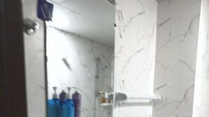 Uma casa de banho com uma pia branca, um espelho e uma área de duche.