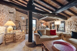 A rustic stone-walled room with a wooden ceiling, a beige sofa, a wooden table, and a lamp. - La Bastide Belle-Pierre - A 25 min de Fréjus (Bagnols-en-Forêt)