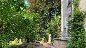 A stone pathway leading to a table and chairs in a lush garden area with stone walls and greenery. - Beautiful country house on the edge of a village, ideal for families! (Compreignac)