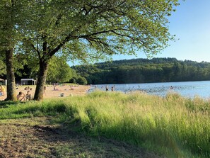 Um parque à beira do lago com praia de areia, áreas gramadas e árvores.