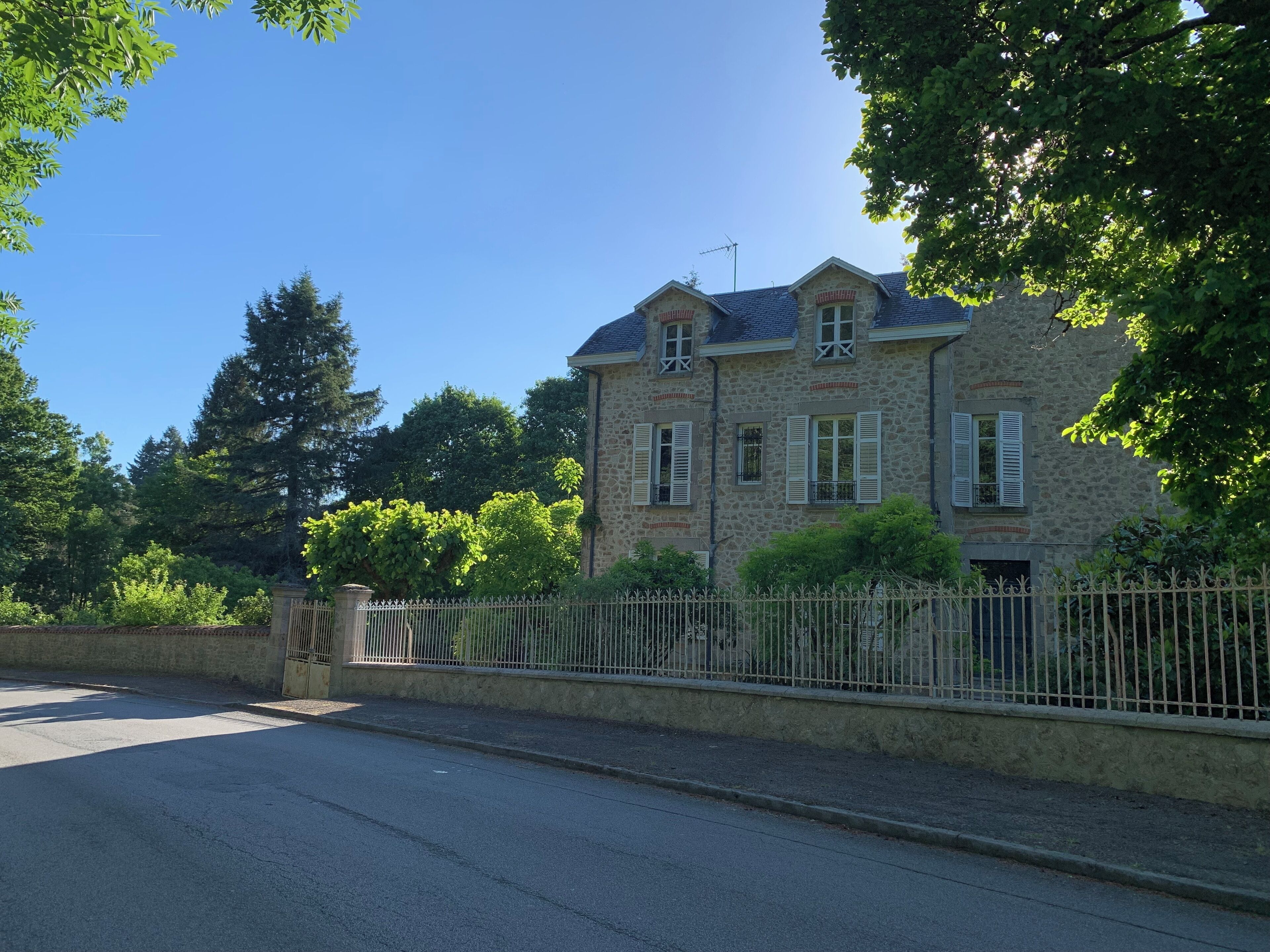 A stone building with a stone facade, multiple windows with shutters, and a gated entrance.