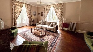 A spacious living room with a sofa, armchairs, a coffee table, and a patterned rug. - Beautiful country house on the edge of a village, ideal for families! (Compreignac)