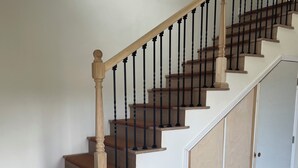 Un escalier en bois avec des balustrades noires et un mur blanc.