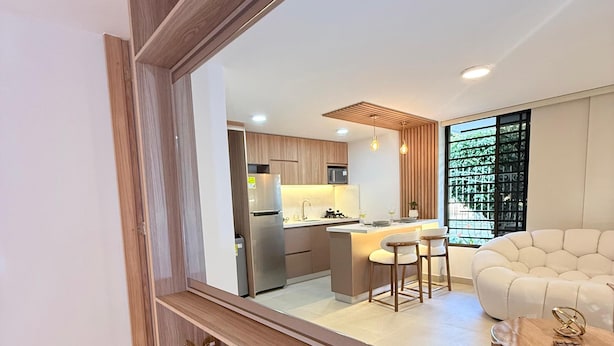 Una sala de estar moderna con un espejo grande, muebles de madera, un sofá y una mesa de centro.