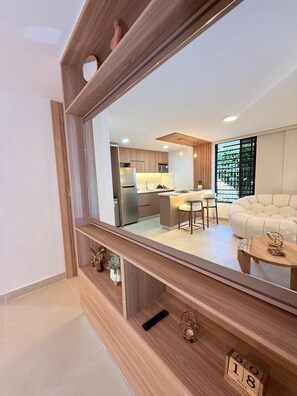 A modern living room with a large mirror, wooden furniture, a sofa, and a coffee table. - Discover modern and stylish apt in Limonar (Cali)