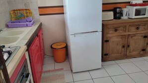 A kitchen with a refrigerator, sink, and wooden cabinets. - Appartement Hibiscus - Ground floor (Le Moule)