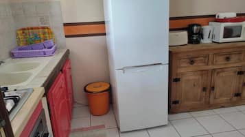Une cuisine équipée d’un réfrigérateur, d’un évier et de meubles de rangement en bois.