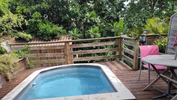 A hot tub on a wooden deck with a wooden fence and greenery in the background. - Appartement Hibiscus - Ground floor (Le Moule)