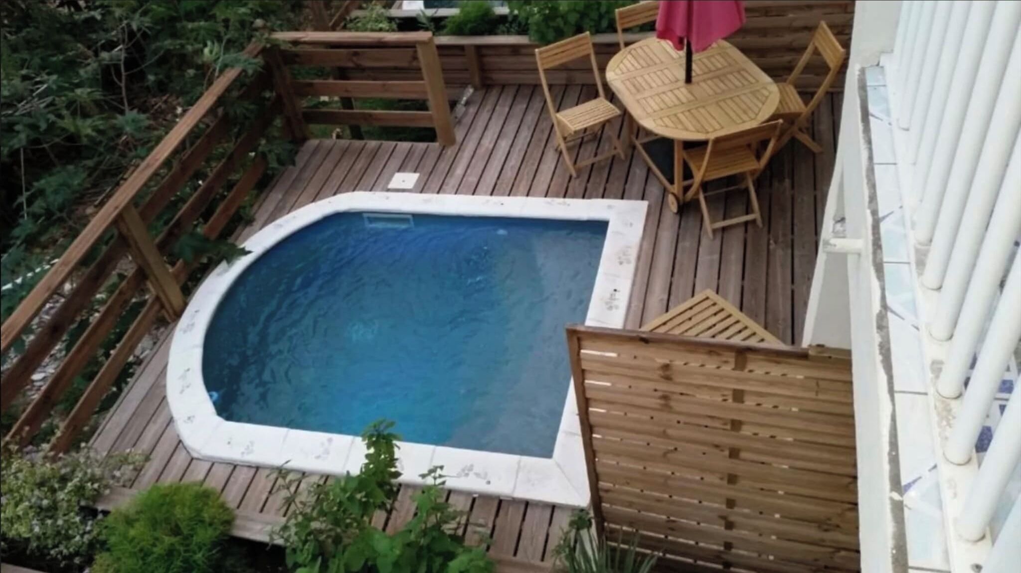 Un bain à remous entouré d’une terrasse en bois, avec une table et des chaises.
