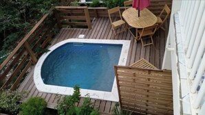 A hot tub surrounded by a wooden deck with a table and chairs. - Appartement Hibiscus - Ground floor (Le Moule)